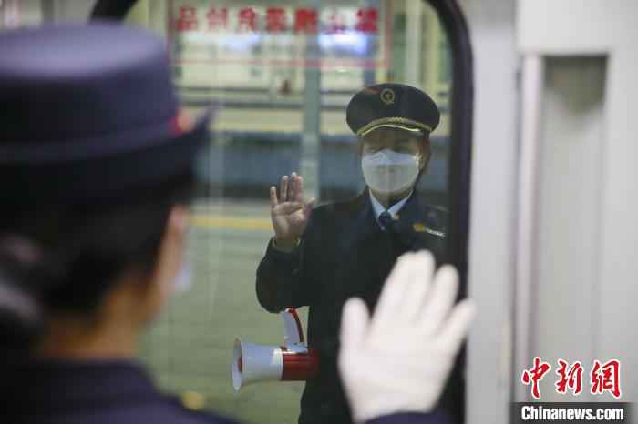 T7次列车即将驶出绵阳站,母亲杨春蓉与女儿李斯羊挥手道别。 李锴 摄 铁路人战“疫”:面对疫情,母女并肩前行