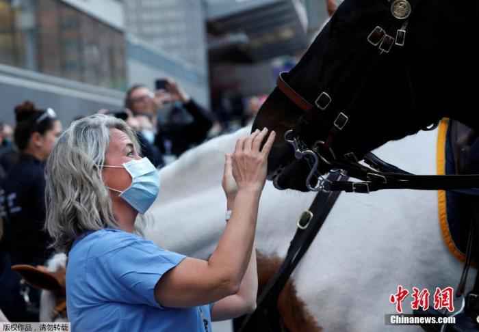 资料图:当地时间4月16日,纽约警察局派出骑警小组抵达纽约朗格尼医学中心慰问医护人员。图为护士和医生在医院外和骑警的战马亲密互动。 工作环境太危险 纽约州护士工会起诉州和两家医院